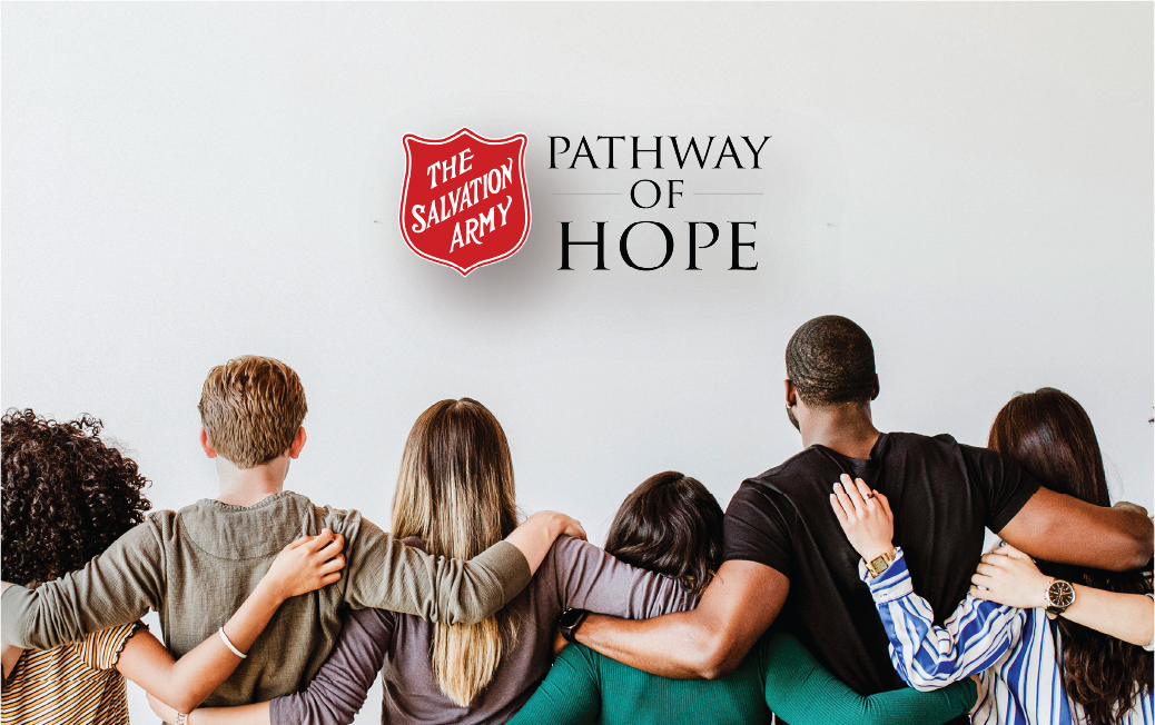 Back view of a group of people standing side by side with arms around each others shoulders beneath The Salvation Army shield logo and the words Pathway of Hope, representing a community support program.